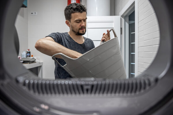 portrait-man-view-from-washing-machine-loading-washing-dirty-linen